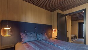 Een slaapkamer met een groot bed, houten paneelwanden en een plafond met houten latten.