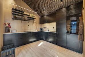 Une cuisine moderne avec des meubles de couleur noire, un plancher en bois et une cuisinière intégrée.