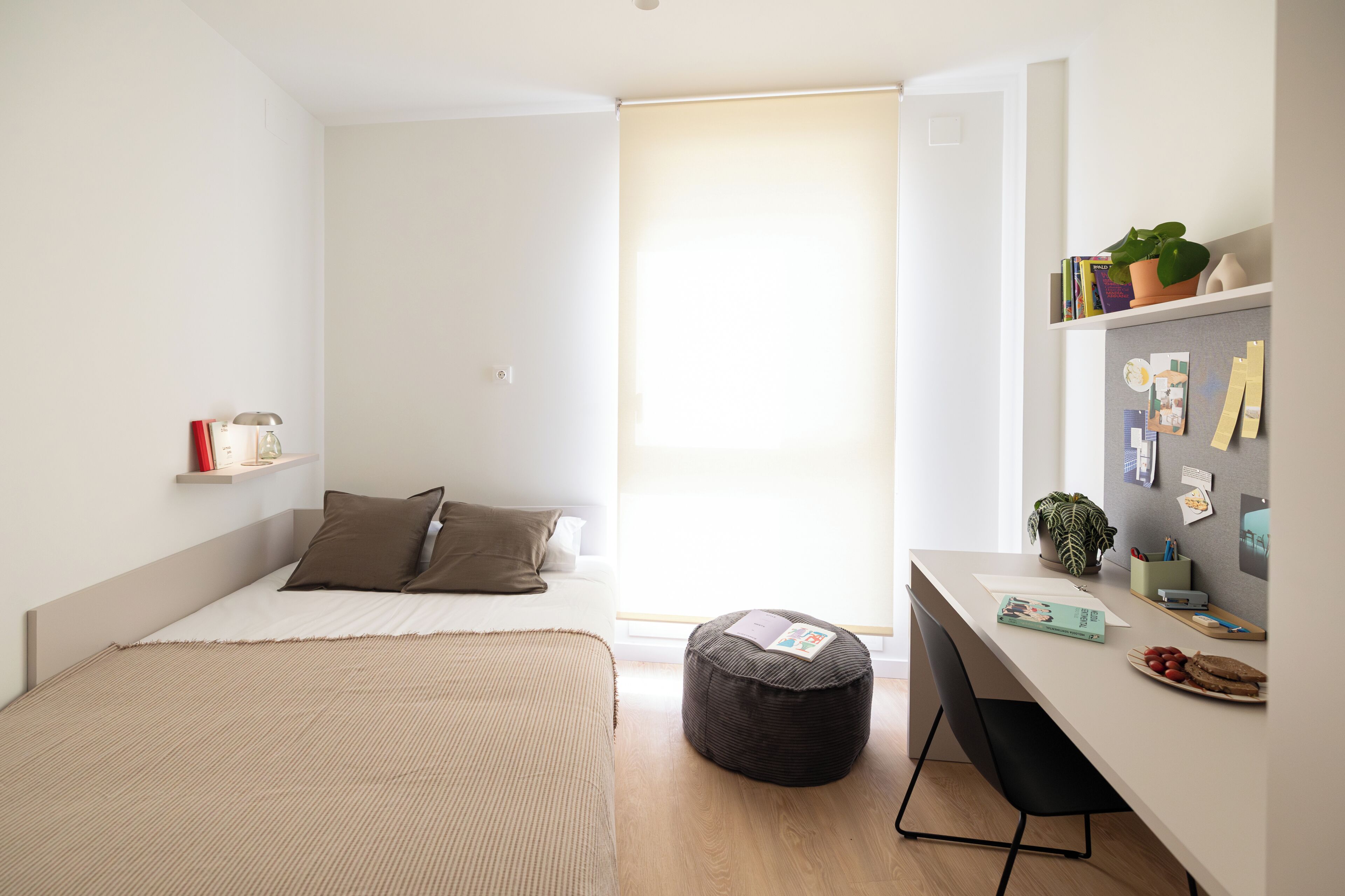 A minimalist bedroom with a bed, a desk, and a window.