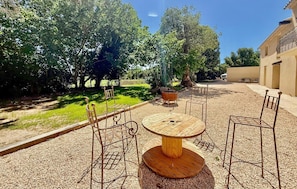 An outdoor patio with a round table and four chairs, surrounded by gravel and trees. - Awesome home in St Martin de Crau (St Martin de Crau)