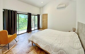 A bedroom with a large bed, a chair, a window with curtains, and an air conditioning unit. - Awesome home in St Martin de Crau (St Martin de Crau)