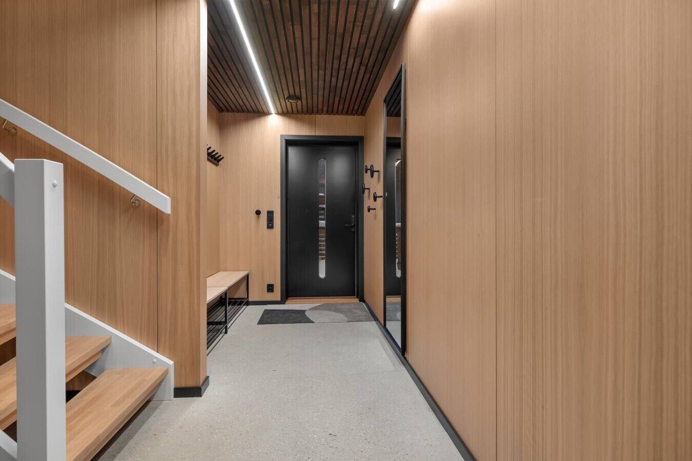 A modern hallway with wooden walls, a bench, and a door.