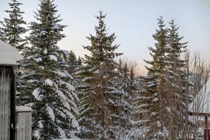 A snowy landscape with tall evergreen trees and a wooden structure. - Signature Townhouse | Arctic Seasons|Luxury Living (Tromsø)