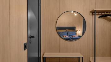 A bedroom with a circular mirror reflecting a bed, a bench, and a wardrobe.