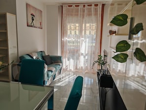 A living room with a sofa, a glass table, and a view through a window with sheer curtains. - CHIARA PARK HOUSE: Your Oasis of Peace Between the City and the Sea (Quartu Sant'Elena)