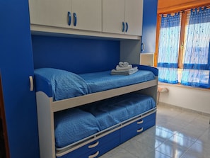 A bunk bed with a lower bunk drawer, a wardrobe with two doors, and a window with curtains. - CHIARA PARK HOUSE: Your Oasis of Peace Between the City and the Sea (Quartu Sant'Elena)