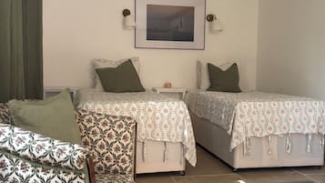 A bedroom with two beds, a nightstand, a lamp, and a framed picture on the wall.