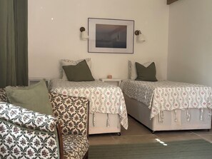 Une chambre avec deux lits, une table de chevet, une lampe et un tableau encadré au mur.