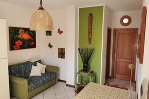 A living room with a sofa, a table, and a door. - La Casa di Sarah in Trinità dAgultu Near the Sea (Trinità d'Agultu e Vignola)