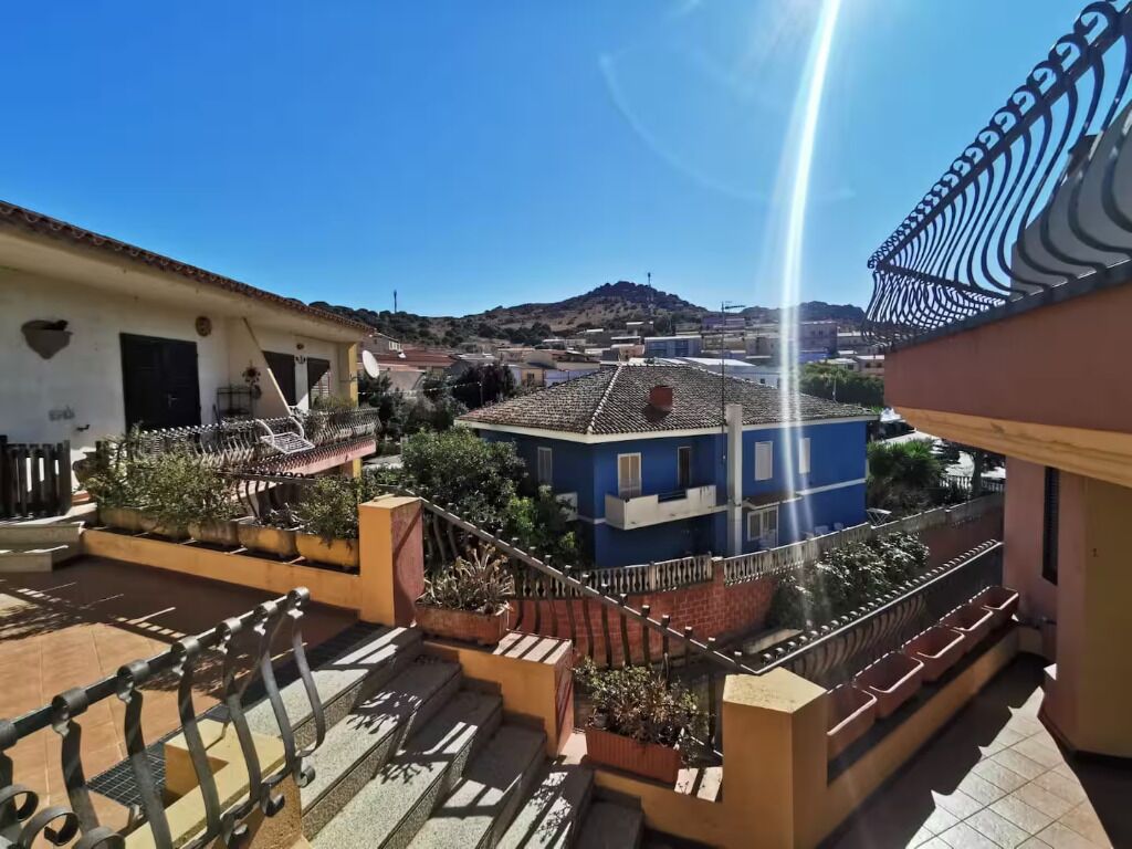 A residential area with a blue building, a staircase, and a view of a hill in the distance.