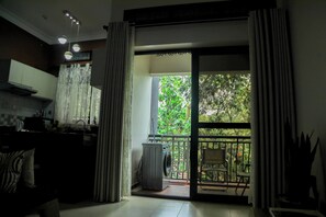 Eine Küche mit Spüle und Schränken, ein Essbereich mit Stühlen und eine Glastür, die auf einen Balkon mit Pflanzen führt.