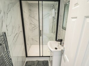 A modern bathroom with a glass-enclosed shower, a white sink, and a marble-tiled floor. - The Ocean House - Sea Whisper (Hunstanton)