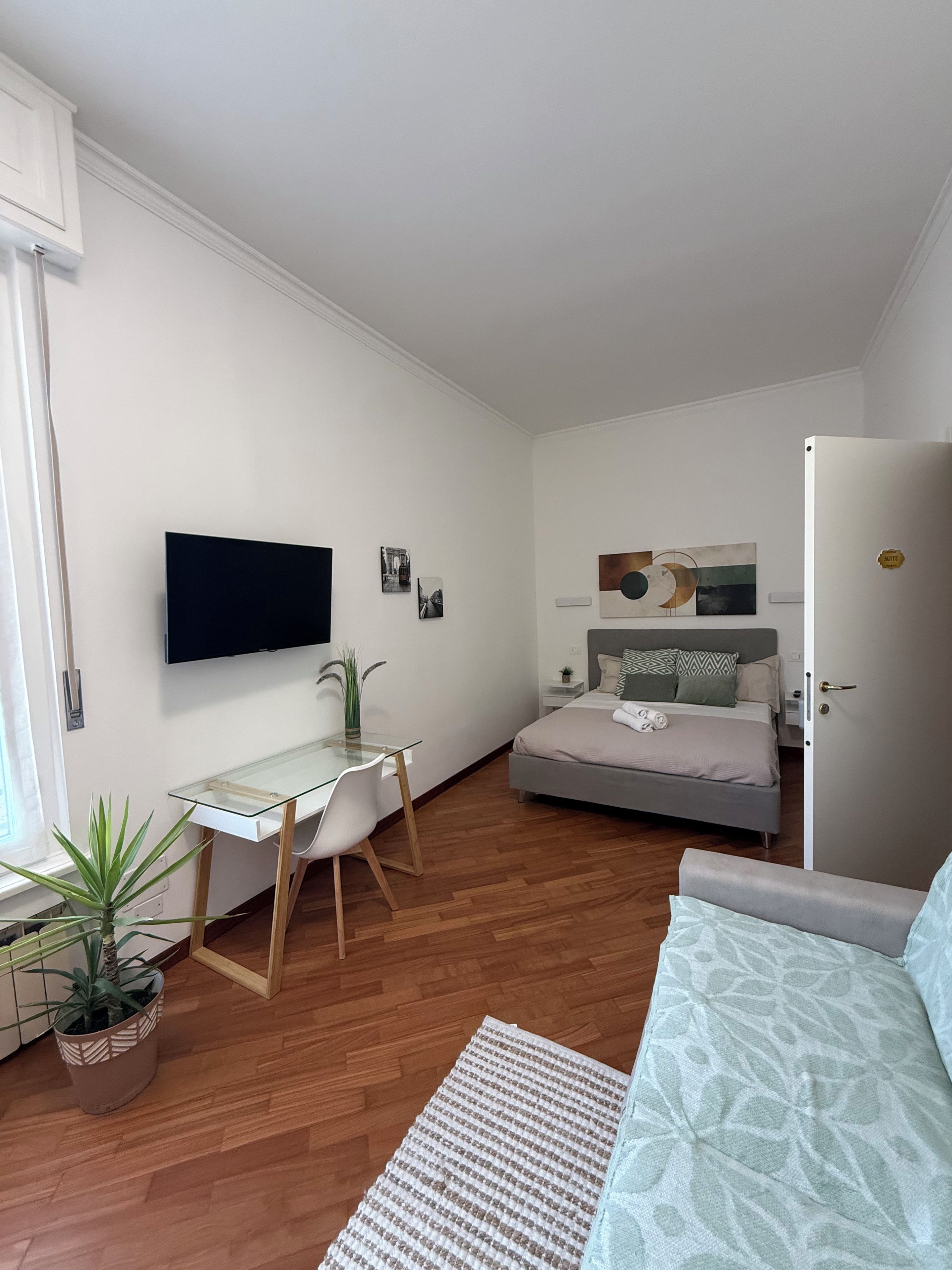 A compact bedroom with a bed, bedside table, and a mounted TV.