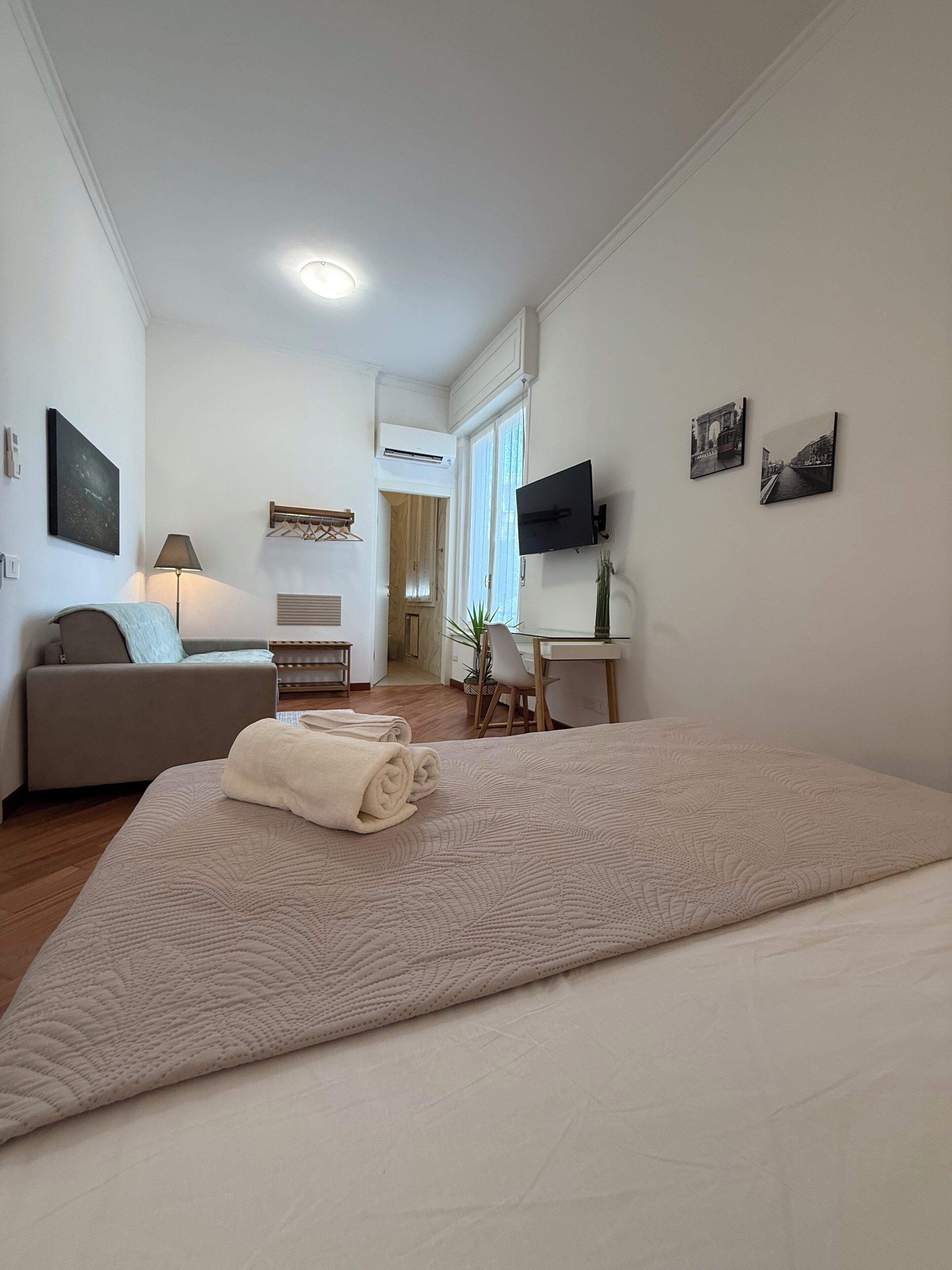 Een hotelkamer met een bed, een bank, een bureau, een televisie en kunstwerken aan de wanden.