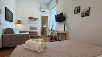 Een hotelkamer met een bed, een bank, een bureau, een televisie en kunstwerken aan de wanden.