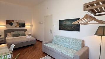 Ein modernes Wohnzimmer mit einer Couch, einem Holztisch, einem Kleiderständer und einem Bett mit Kopfteil.