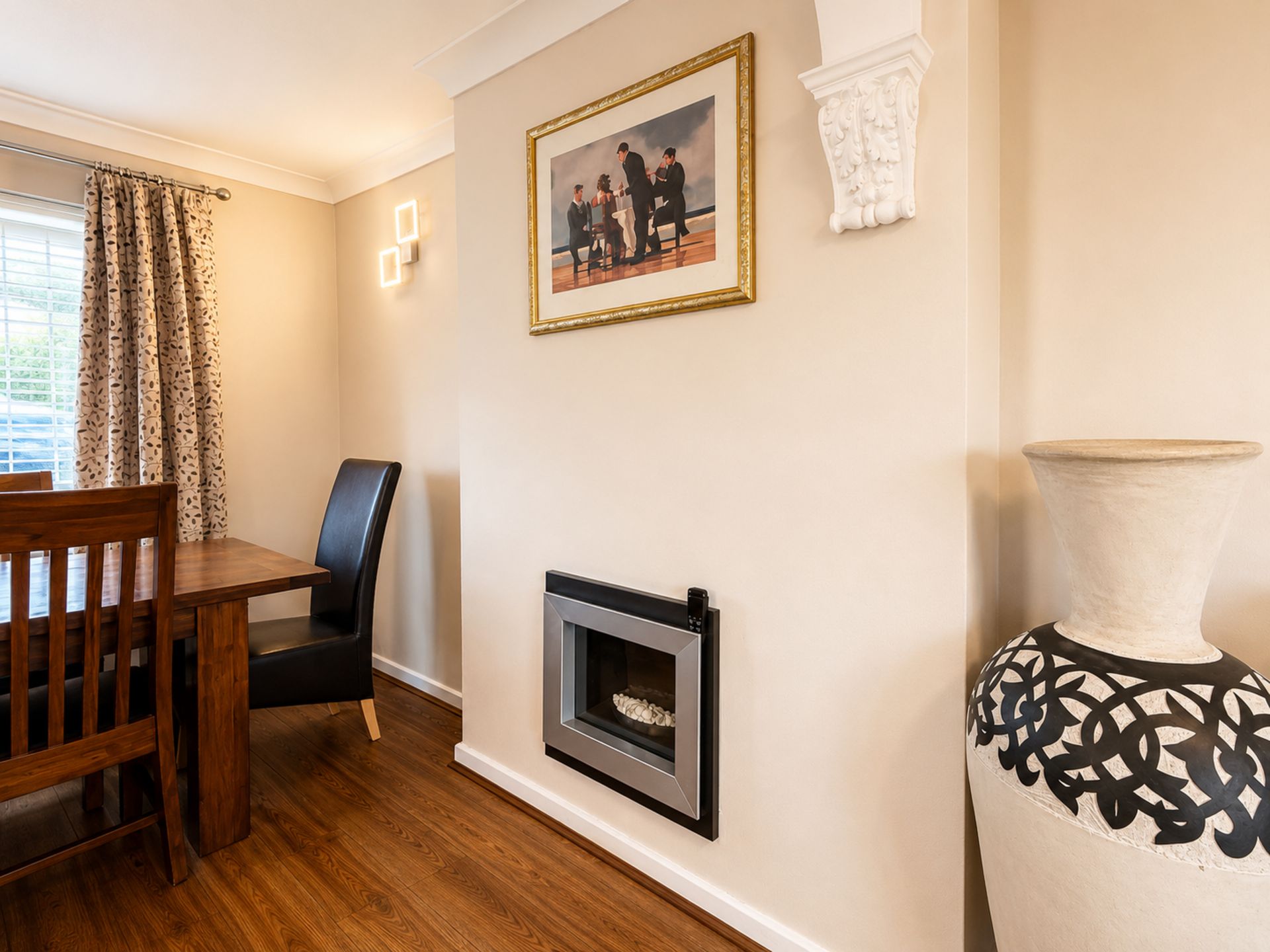 A dining area with a wooden table and chairs, a fireplace, and a framed picture on the wall.