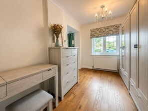 A room with a wooden desk, a bench, a dresser, a radiator, and a window with a view.