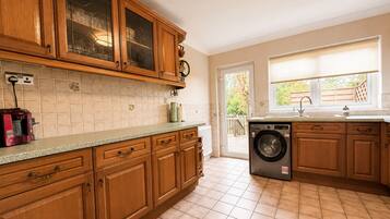 A kitchen with wooden cabinets, a built-in washing machine, and a window with a view.
