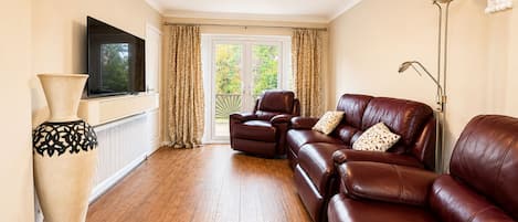 A living room with a leather sofa, a television, and a large vase.