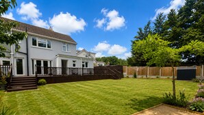 A residential property with a well-maintained lawn, a wooden deck, and a house with a tiled roof. - Spacious 4BDR Home in Rayleigh Essex (Essex)