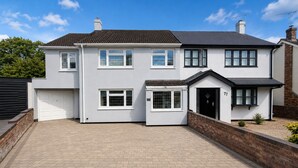 A two-story residential building with a garage, a driveway, and a brick wall. - Spacious 4BDR Home in Rayleigh Essex (Essex)