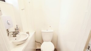 A small bathroom with a white toilet, a sink, and a mirror. - The Ocean House - Sea Shell (Hunstanton)