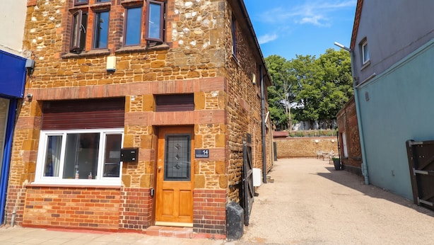 A traditional stone building with a wooden door, multiple windows, and a visible number '14' sign. - The Ocean House - Sea Shell (Hunstanton)
