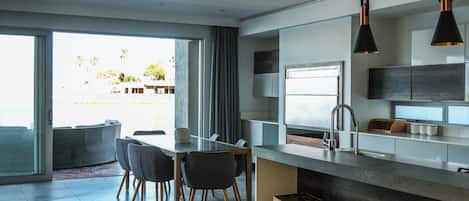 A modern kitchen with a large island, bar stools, and a view of the outdoors.