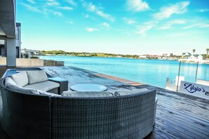 A waterfront outdoor seating area with a wicker sofa and a small round table. - 
Your perfect Beach Escape in Zifaja Living Marina, Relax and Make Memories (Jeffreys Bay)