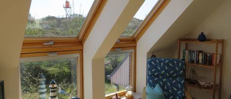 A room with skylights, a chair, a bookshelf, and a small table.