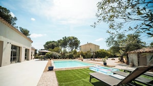 A backyard with a swimming pool, lounge chairs, and a building with a tiled roof. - La Vila Fontaine - Nîmes - Air Conditioning - Swimming Pool (Langlade)