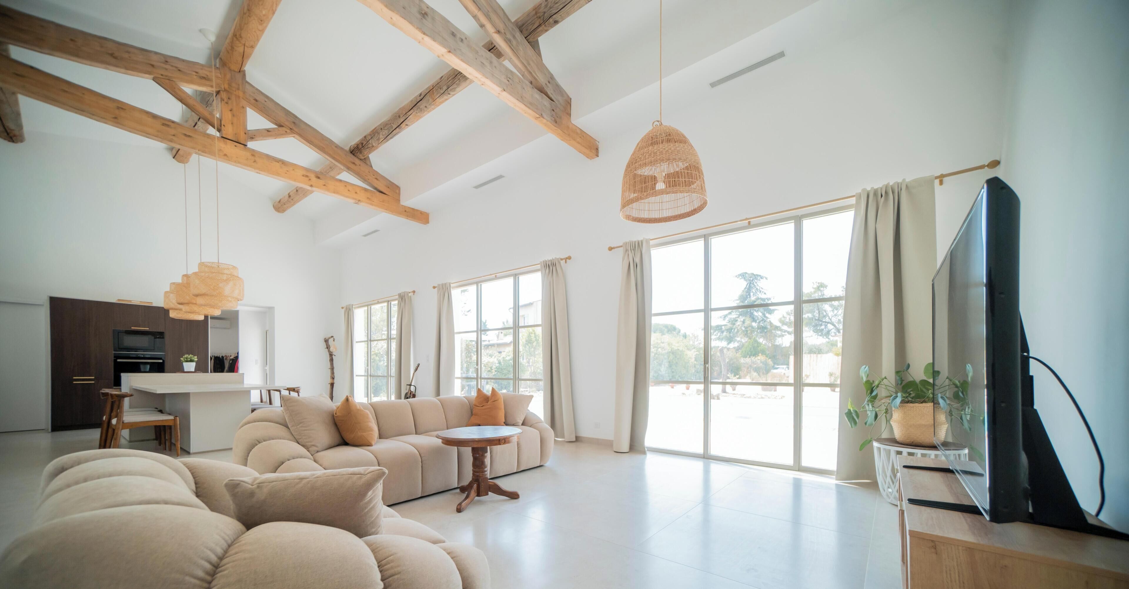 A spacious living room with a large sofa, a dining table, and a television.