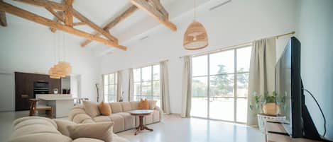 A spacious living room with a large sofa, a dining table, and a television.