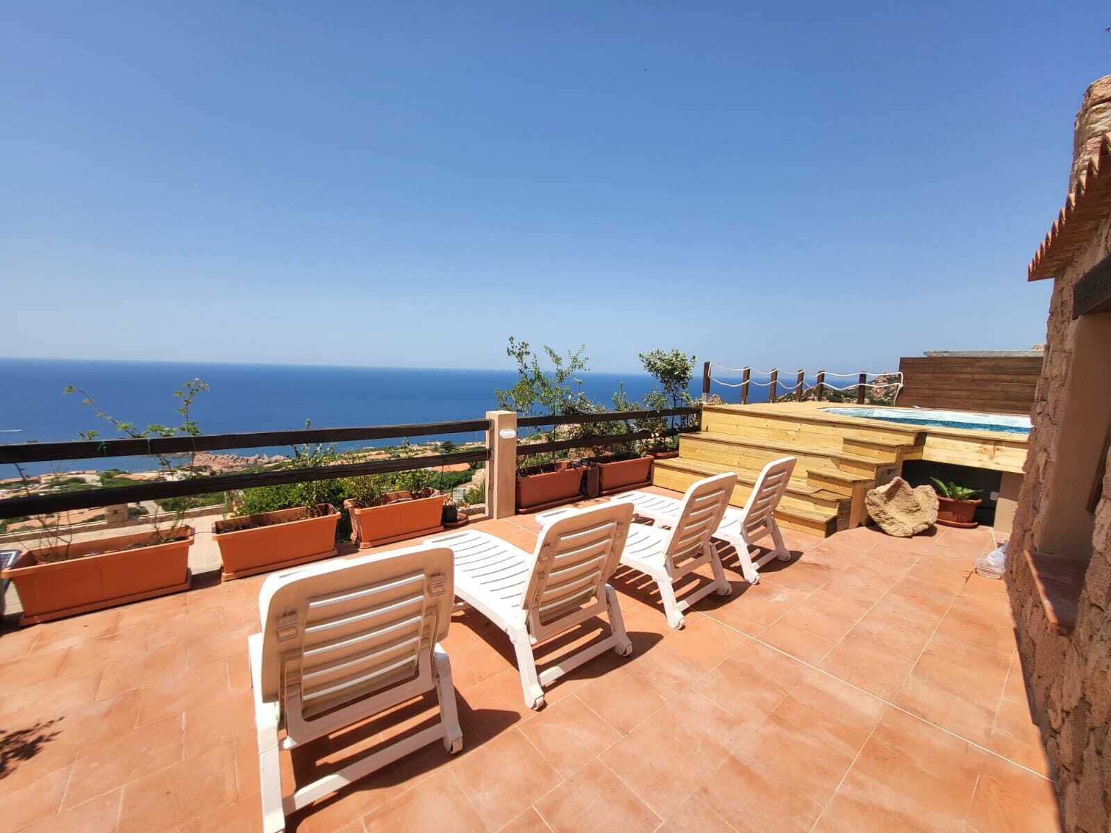Eine Terrasse mit Sitzgelegenheiten im Freien, einem Pool und Meerblick.