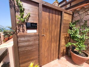 A wooden gate with a house number sign, a potted plant, and a stone wall. - Villa with panoramic ocean views and private pools (Trinità d'Agultu e Vignola)