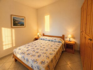 A bedroom with a bed, two bedside tables, a nightstand, a wooden wardrobe, a painting on the wall, and a window. - Villa with panoramic ocean views and private pools (Trinità d'Agultu e Vignola)