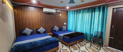 A hotel room with two beds, a ceiling fan, an air conditioning unit, and a patterned floor.