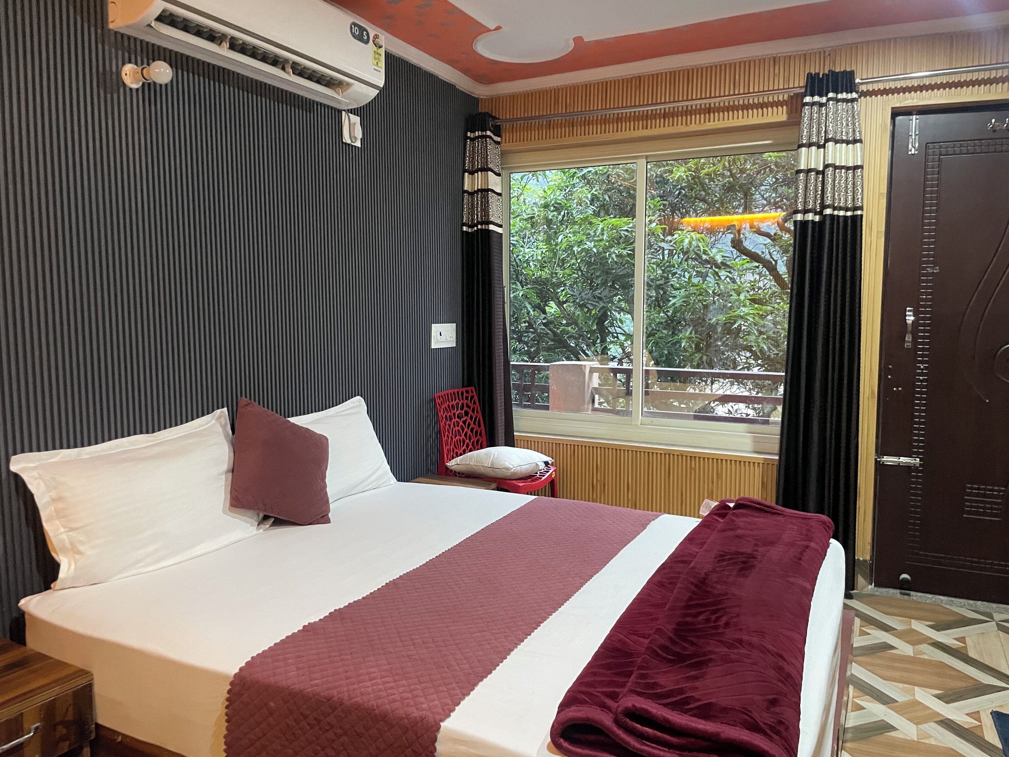 A hotel room with a bed, a window with curtains, a door, and a radiator.