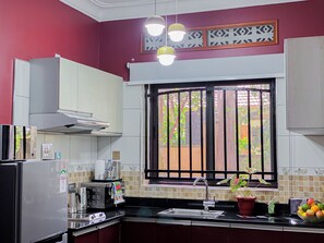 Une cuisine équipée d’un réfrigérateur, d’un four à micro-ondes, d’un évier et d’une fenêtre donnant sur un espace verdoyant.