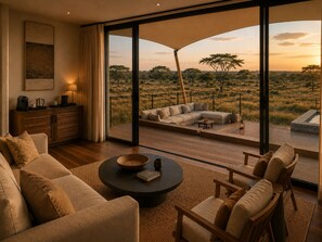A modern living room with a large sliding glass door leading to an outdoor deck with a view of a savannah landscape. - Zuraya Serengeti (Makoma)