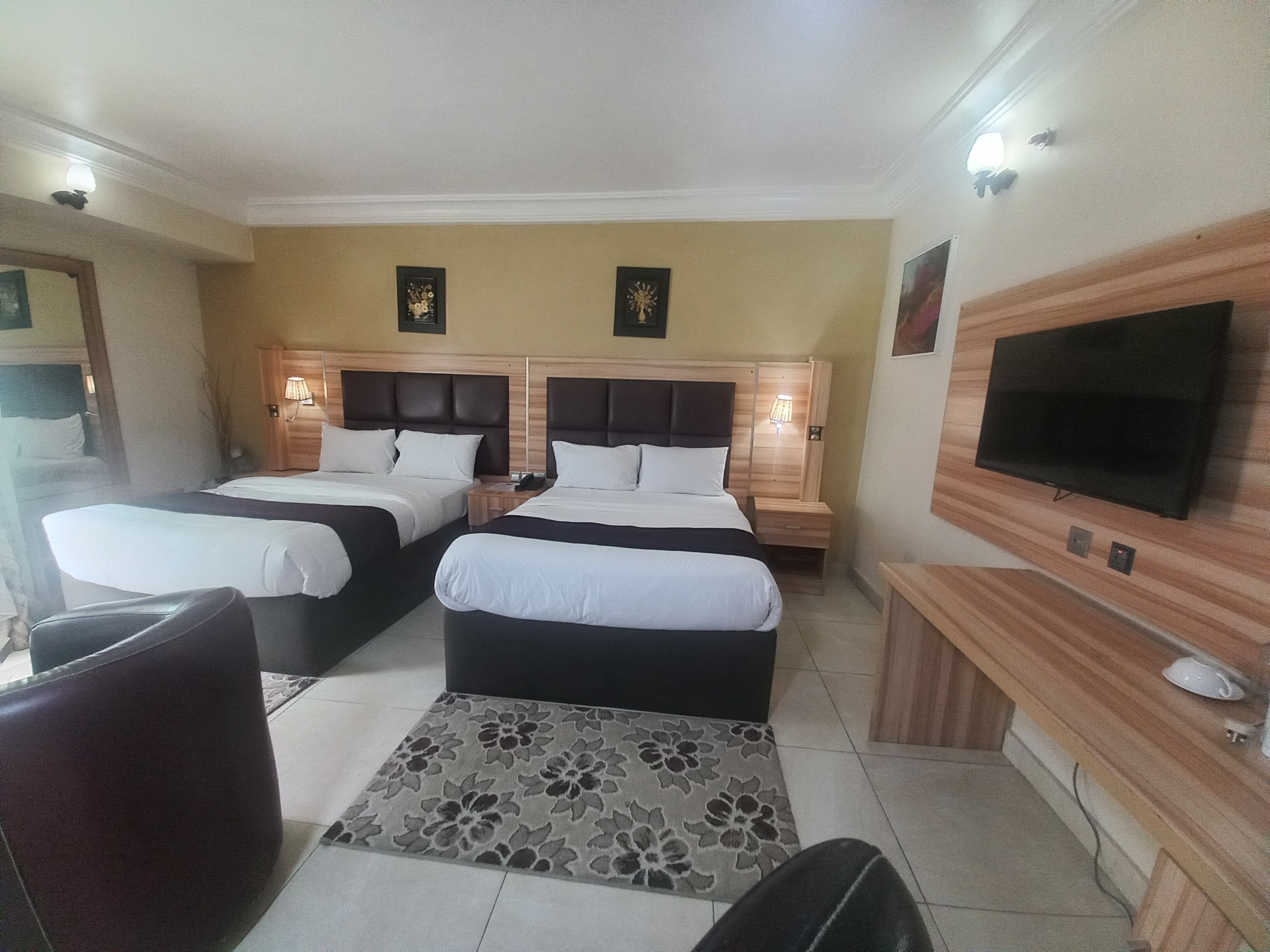 Habitación de hotel con dos camas, un televisor, un escritorio y una silla.