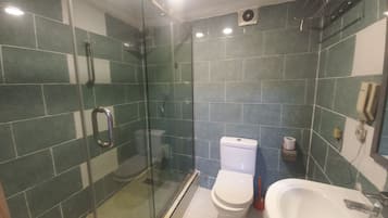 A bathroom with a glass-enclosed shower, a toilet, and a sink.