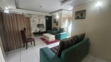 Uma sala de estar com um sofá, uma televisão e uma mesa de centro.