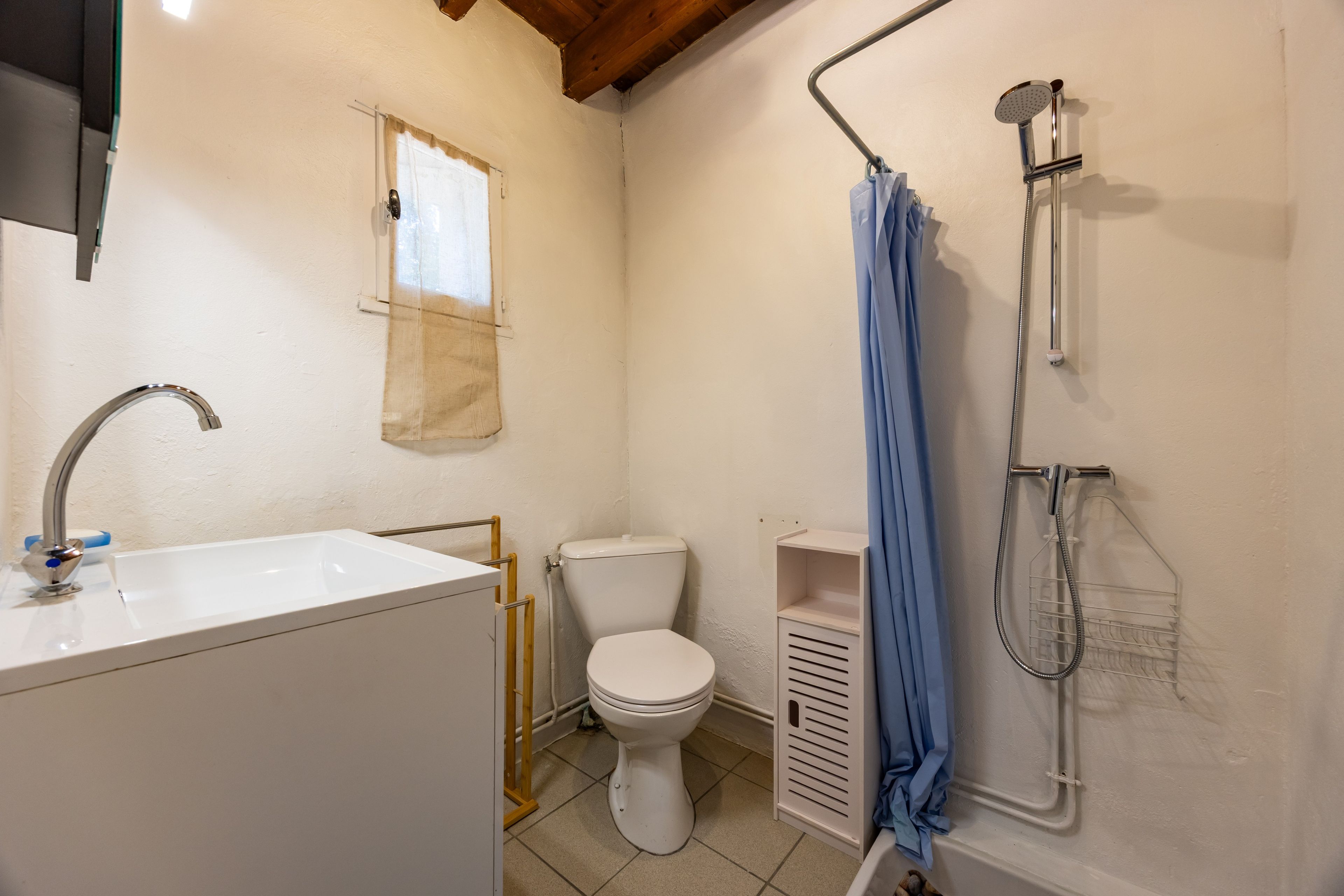 Ein kleines, sauberes Badezimmer mit Waschbecken, Toilette und Dusche, alles in Weiß.