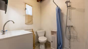 Ein kleines, sauberes Badezimmer mit Waschbecken, Toilette und Dusche, alles in Weiß.