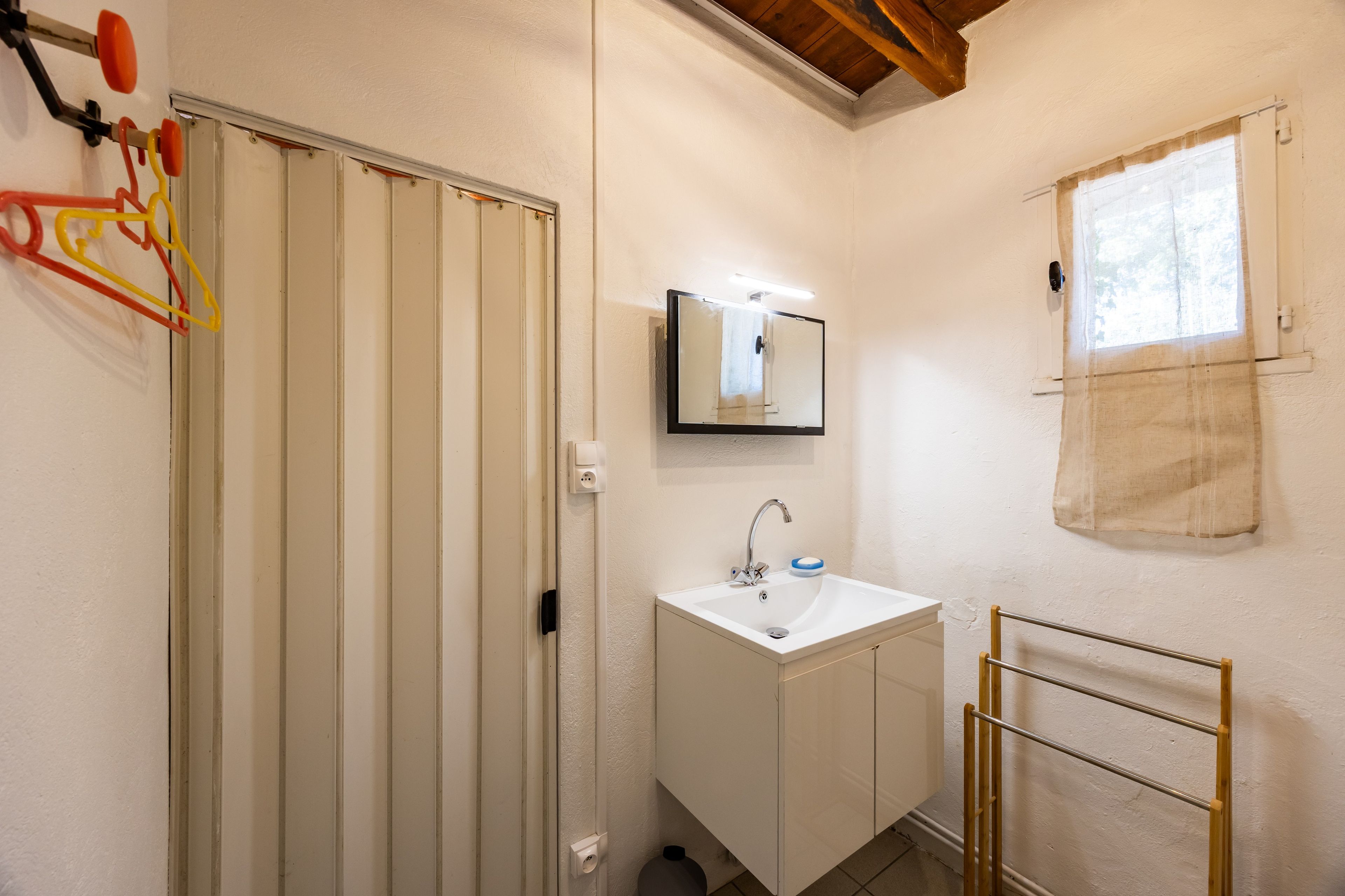 A bathroom with a white sink, mirror, and towel rack.