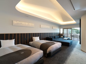 Quarto de hotel moderno com duas camas, um sofá e varanda com área de estar externa.