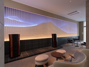 Um lobby moderno com área de estar, parede decorativa com painéis verticais e uma grande janela.