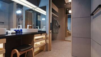 A modern bathroom with a large mirror, dual sinks, and a wooden chair.